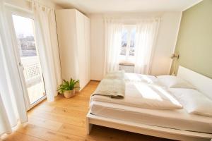 una camera bianca con un letto e due finestre di Residence Isarcus a Bressanone