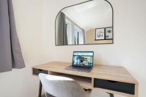 a laptop sitting on a wooden desk in front of a mirror at Central MK House with Free Parking, Fast Wifi, and Smart TV with Xbox, Sky TV Packages and Netflix by Yoko Property in Milton Keynes