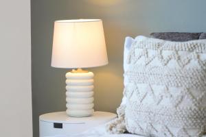 ミルトン・キーンズにあるCentral MK House with Free Parking, Fast Wifi, and Smart TV with Xbox, Sky TV Packages and Netflix by Yoko Propertyの枕の横のテーブルに置かれた白いランプ
