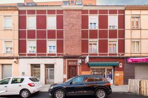 dos autos estacionados en una calle frente a un edificio en Pop Gallery en León