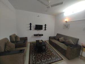 ein Wohnzimmer mit einem Sofa und einem TV in der Unterkunft NK Homes -Serviced Apartments - 2 BHK Homestay, Fast Wifi, Fully Furnished in Hyderabad