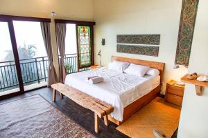 a bedroom with a bed with a bench and windows at Villa Jado 3 - Lake and Mountain View Villa in Bedugul