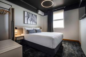 Un dormitorio con una cama grande y una ventana en Nightcap at Empire Hotel en Gepps Cross