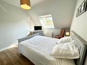 een witte slaapkamer met een bed en een raam bij Maison de vacances – Jardin – 5 min des plages in Guidel