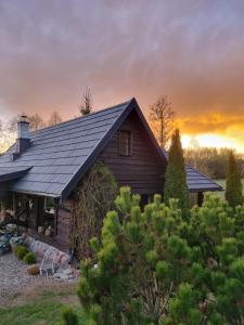 a house with a gambrel roof with a sunset in the background at Wiejska Chata in Barczewo