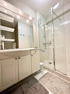 een witte badkamer met een wastafel en een douche bij Maison de vacances – Jardin – 5 min des plages in Guidel