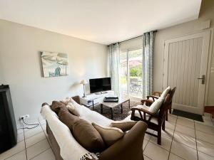 een woonkamer met een grote bank en een tv bij Maison de vacances – Jardin – 5 min des plages in Guidel