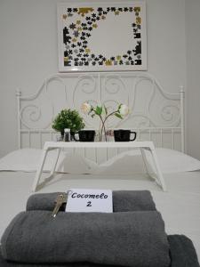 Una cama blanca con una mesa con un cartel. en Cocomelo Apts 2, en Heraclión