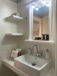 a white bathroom with a sink and a mirror at Aggelos Studios in Adamantas