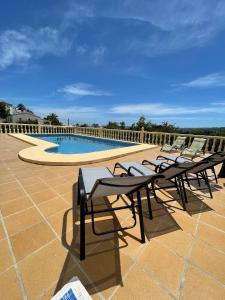 una fila de mesas y sillas junto a una piscina en Casa de Huéspedes , Villa Adriana, en Jávea