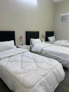 three large beds in a room with white sheets at Alamjed Residence in Mecca