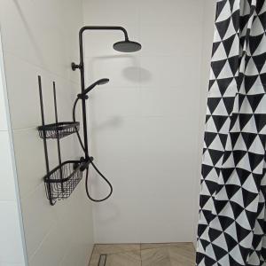 a shower in a bathroom with a black and white curtain at Domki Bukowy Las in Rewa