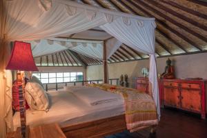 une chambre avec un lit à baldaquin avec une lampe rouge dans l'établissement Chalet Rabina, à Ubud