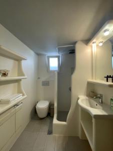 Baño blanco con aseo y lavamanos en Aggelos Studios, en Adamas