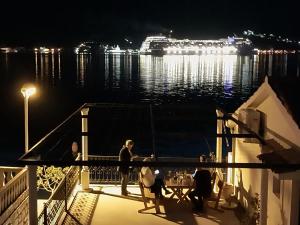 a group of people sitting at a table on a deck at night at Apartments Ponta in Kotor