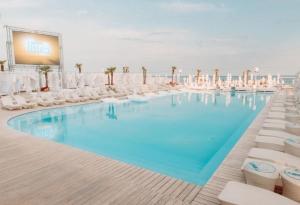 a swimming pool with white chairs and a screen at Apartments Arcadia VIP in Odesa