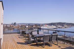 a deck with tables and chairs and a boat in the water at Tjuvholmen / Aker Brygge - Most expensive area in Oslo! in Oslo