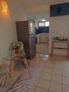 a kitchen with a glass table and a stainless steel refrigerator at Cibuqueira numéro 7, Centre ville, vue sur mer , plage à pied in Le Moule