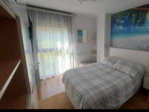Un dormitorio con una cama y una ventana grande en Alojamientos Marte apartamento a pie de playa y garaje, en Suances