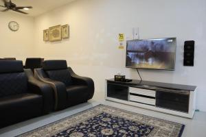 a living room with two chairs and a flat screen tv at Dudu Guesthouse Kuala Kangsar in Kuala Kangsar