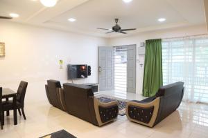 a living room with chairs and a table and a television at Dudu Guesthouse Kuala Kangsar in Kuala Kangsar