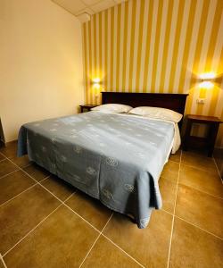 a bedroom with a bed with a blue blanket on it at Hotel Giardino in Follonica