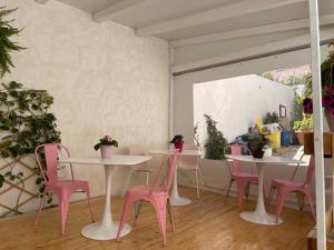 サン・ヴィート・ロ・カーポにあるB&B Chiedi la Lunaのテーブル2台とピンクの椅子が備わる部屋