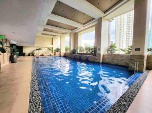 uma grande piscina com água azul no átrio do hotel em Nice and Cozy Studio near Greenbelt Makati with Balcony em Manila