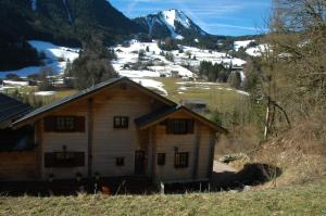 uma cabana de madeira com uma montanha coberta de neve ao fundo em Chalet Etoile em Abondance