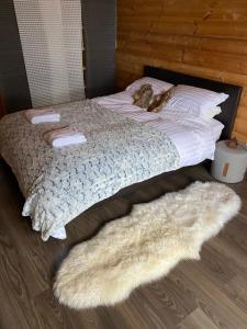a bed with white sheets and pillows and a furry rug at Chalet Etoile in Abondance