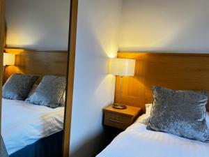 a bedroom with two beds and a mirror at Herriots Hotel in Skipton