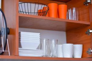 a cabinet with plates and cups and orange cups at Comfy, stylish, and family-friendly apartment in Karatina Town in Karatina