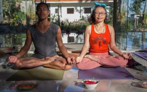 un hombre y una mujer sentados en una pose de yoga en Ara Garden Inn, Accommodation, Yoga studio & Spa en Ruteng