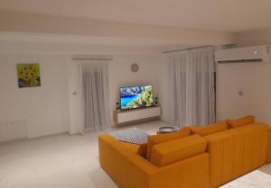 uma sala de estar com um sofá laranja e uma televisão de ecrã plano em Jan-Air em Ilinden