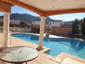 a swimming pool with a glass table and a patio at Villa plain pied avec piscine privée 8 personnes in La Crau