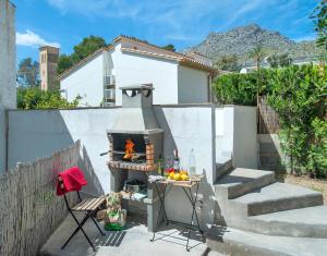 a patio with a stove with a table and a chair at Owl Booking Villa Mariner - 5 Min Walk to the Beach in Pollença