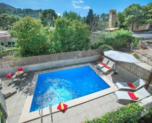 a swimming pool with chairs and umbrellas and a table at Owl Booking Villa Mariner - 5 Min Walk to the Beach in Pollença