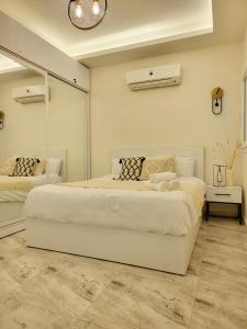 una grande camera bianca con due letti e uno specchio di Selena Bay Resort - Luxury 2 Bed Apt with Private Beach a Hurghada