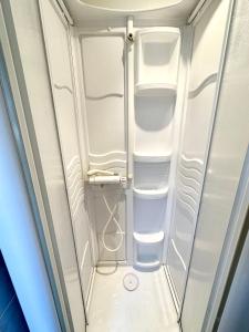 a small white refrigerator with white shelves at Maison de charme – Terrasse – 5min des plages in Port-Louis