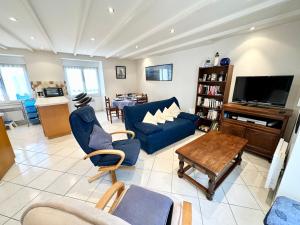 a living room with a blue couch and a tv at Maison de charme – Terrasse – 5min des plages in Port-Louis