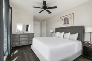 um quarto com uma cama branca e uma ventoinha de tecto em Breathtaking Condos Near French Quarter em Nova Orleans
