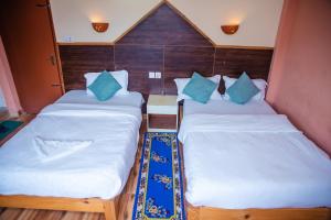 2 aparte bedden in een kleine kamer met houten lambrisering bij Hotel Olympus Pokhara in Pokhara