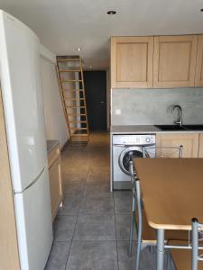 uma cozinha com uma mesa, um fogão e uma máquina de lavar louça em Appart 30 m2 cosy 2 personnes 1 grande chambre en mezzanine em Saint-Mitre-les-Remparts