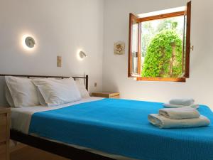 a bedroom with a bed with blue sheets and a window at Imeros in Chania Town