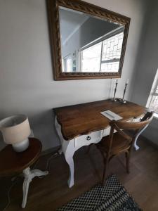 a mirror on a wall with a desk and a chair at Nel's Cottage, a private and peaceful cottage in Benoni