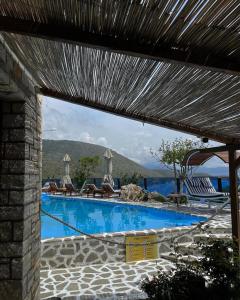 a swimming pool with chairs and a view of the water at Palermiti Luxury Rooms in Himare