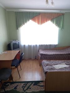 Zimmer mit 2 Betten, einem Tisch und einem Fenster in der Unterkunft Готель Поділля in Shestakovka