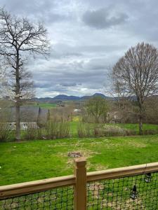 a fence with a view of a field of grass at Tiny House L’œil des Dômes in Saint-Pierre-le-Chastel