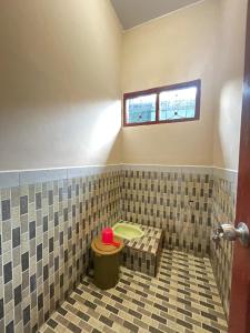 a tiled bathroom with a toilet and a window at Elnara in Mandati