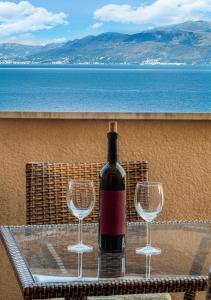 a bottle of wine sitting on a table with two wine glasses at Apartment Zen u Postira in Postira